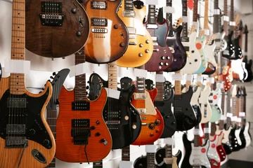 Abwaschbare Fototapete Musikladen Reihen von verschiedenen Gitarren im Musikladen