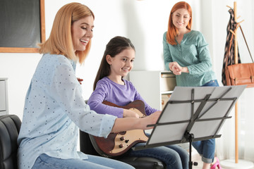 Obraz premium Little girl with her teacher and mother at music lesson. Learning notes