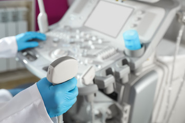 Sonographer holding ultrasound machine probe in clinic, closeup with space for text