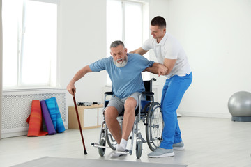 Professional physiotherapist working with senior patient in rehabilitation center