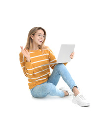 Young woman in casual outfit with laptop sitting on white background