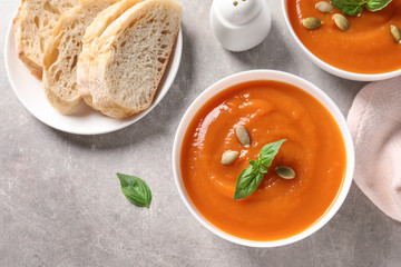 Flat lay composition with bowls of tasty sweet potato soup on grey background