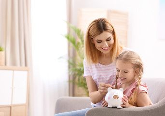 Family with piggy bank and money at home. Space for text