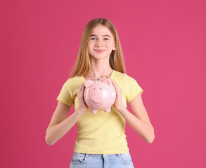 Fototapeta na wymiar Teen girl with piggy bank on color background