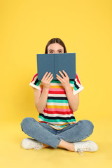 Young woman reading book on color background, space for text