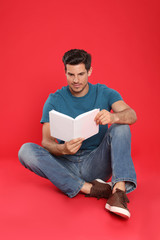 Handsome man reading book on color background, space for text