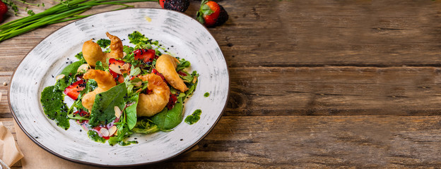 Delicious light salad with grilled shrimps, strawberries, arugula, parsley, spinach and scallion, sprinkled with fried sesame seeds and seasoned with green spinach sauce. Banner