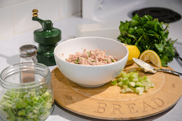 Healthy tuna salad being prepare with fresh ingredients, celery, lemon, onion, mayo and greens