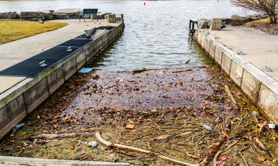 Concrete pier surrounds boat docking area with cleats,debris and garbage collects in the corners