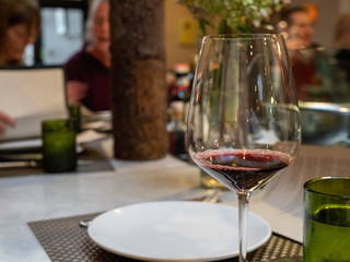 Glass of red tasting wine in restaurant with patrons dining
