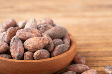 dried cacao beans in the wooden bowl, on the wooden board