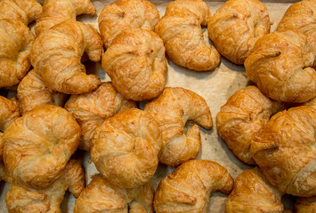 Pile of fresh baked mouthwatering almond croissant pastries in the basket. Fresh Baked Croissants . A pile of tasty crispy croissant in basket. It is freshly baked in pastry kitchen. 