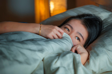 home lifestyle portrait of young beautiful sad and depressed Asian Chinese woman awake in bed late night suffering anxiety crisis and depression problem feeling desperate
