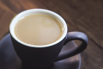 cup of coffee with milk on a wooden kitchen table.