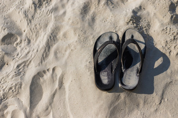 Summer holiday concept. Black pair of sandals on beach.
