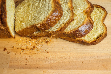 Slice Brioche toast loaf with bread crumbs on wood cutting board	