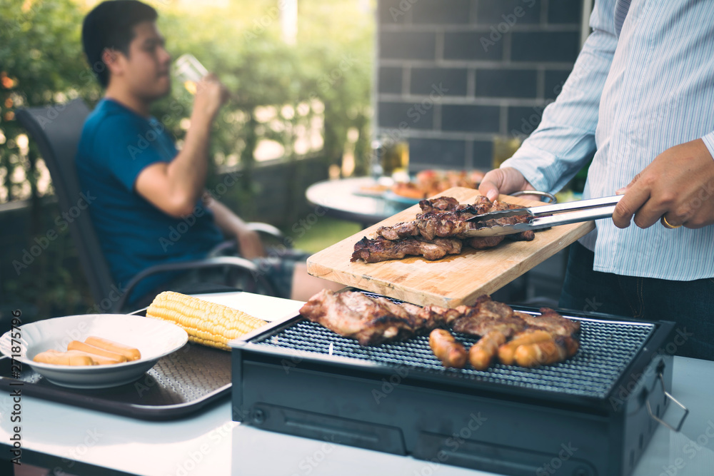 Wall mural asian men are pinching pork on a wooden cutting board and holding it to friends who are celebrating 