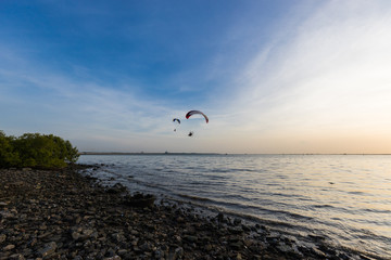 Silhouette of Paramotors flying to sky on sunset.