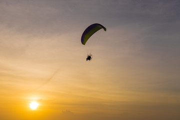 Silhouette of Paramotors flying to sky on sunset.