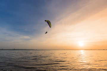 Silhouette of Paramotors flying to sky on sunset.