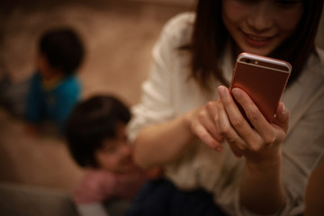 スマートフォンの操作に夢中になる母親