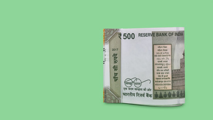Folded set of Indian 500 Rupee currency bills isolated on green background