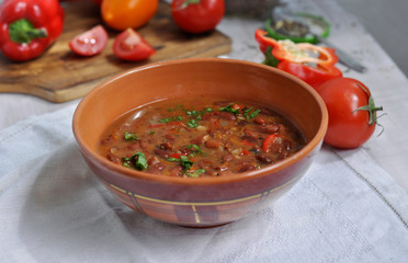 Spicy red beans. Hot homemade bean soup with tomatoes and peppers in a ceramic bowl.