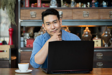 Asian man in deep thought closeup in profile with laptop.