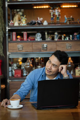 Asian man in deep thought closeup in profile with laptop.