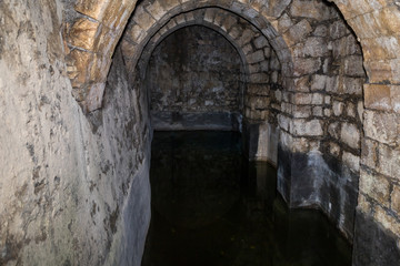 Fototapeta na wymiar Surviving underground reservoir partially filled with water in ancient ruins of Pools of Bethesda in the old city of Jerusalem, Israel