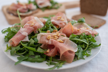 Healthy salad with prosciutto, tomato and green leaves