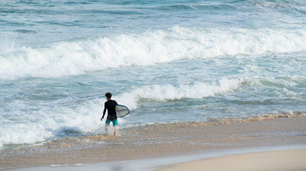 A surfer getting ready for the surf, going surfing in ocean