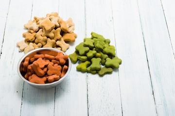 portion of dog food at tin bowl, brown and green heap of feed on floor