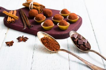 chocolate truffles, cocoa powder, broken dark chocolate on white wooden