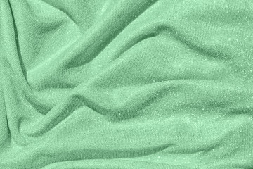 Trendy mint colored Background of draped fabric with silver lurex thread. Beautiful fashionable fabric with a shiny thread for making clothes. Textile background texture.