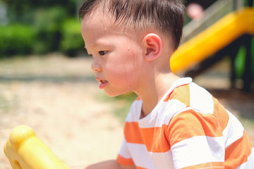 Fototapeta na wymiar Cute little Asian 2 - 3 years old toddler baby boy child sweating during having fun playing, exercising outdoor at playground on nature at park, Heat stroke and summer sunstroke risk symptom concept