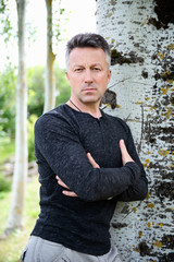 Handsome man. Outdoor male portrait. Single attractive mid-adult man posing in spring park near tree.