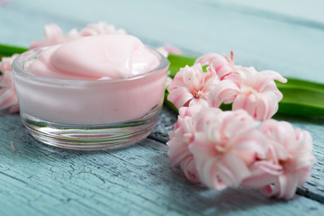cosmetic creams with pink hyacinth flowers, on old cracked blue table