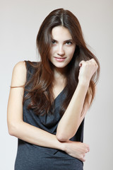 Fashion model. Young woman posing in studio. Beautiful caucasian smiling girl over gray background, image toned.