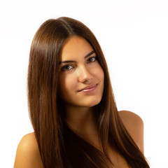 Fototapeta premium Beauty feminine portrait of female face with healthy natural skin. Beautiful tanned teen girl with long brown hair looking at camera. Pretty attractive young woman posing at studio, isolated on white
