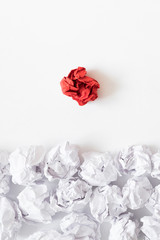 Ideology concept. Flat lay of crumpled same color paper ball pile against individual red one. White background. Copy space.