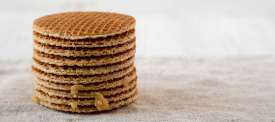 Stack of homemade Dutch stroopwafels with honey-caramel filling on cloth, side view. Copy space.