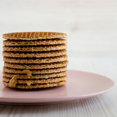 Stack of homemade Dutch stroopwafels with honey-caramel filling on a pink plate, side view. Close-up.