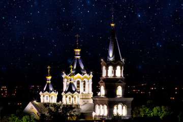 Fototapeta na wymiar Ornate facade of the Church in Zhytomyr, Ukraine, illuminated at night, Star sky