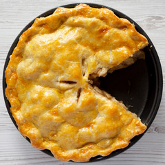 Homemade apple pie on a white wooden surface, top view. Flat lay, overhead, from above. Close-up.
