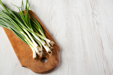 Chopped green onions on a rustic wooden board, low angle view. Space for text.