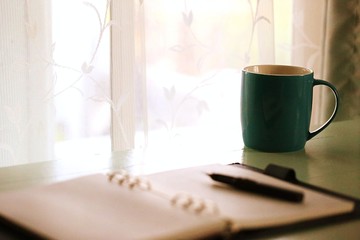 Blank paper and pen closeup coffee cup on table interior window