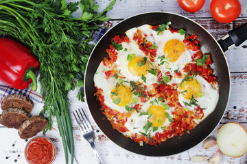 Shakshouka with five cooked eggs on top of tomato sauce in cast iron skillet	
