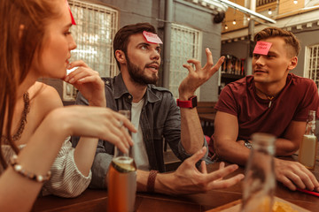 Attractive man playing a hedbanz game along with friends