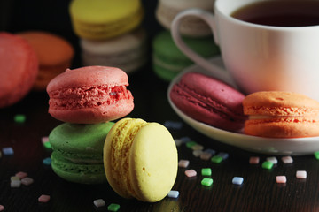 Bright macaroons with a cup of coffee against dark background